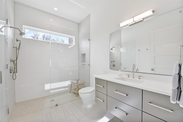 full bath featuring tiled shower, vanity, and toilet