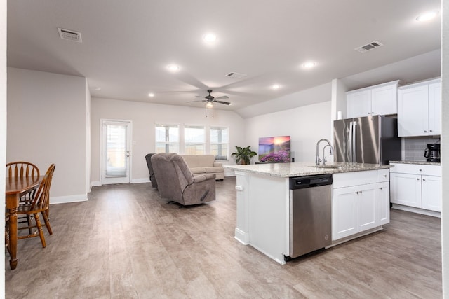 kitchen with a center island with sink, visible vents, appliances with stainless steel finishes, open floor plan, and white cabinets