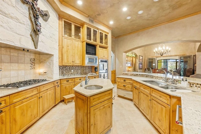 kitchen featuring glass insert cabinets, appliances with stainless steel finishes, a center island, pendant lighting, and a sink