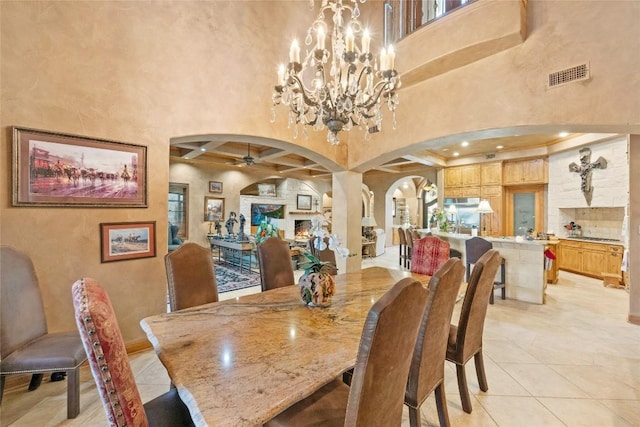 dining area with arched walkways, ceiling fan with notable chandelier, a high ceiling, visible vents, and beam ceiling