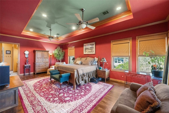 bedroom with ornamental molding, wood finished floors, a raised ceiling, and visible vents