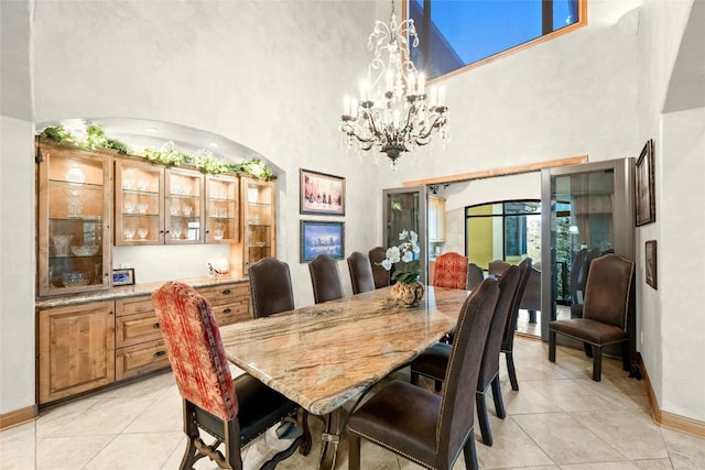 dining space with light tile patterned flooring, a towering ceiling, and baseboards