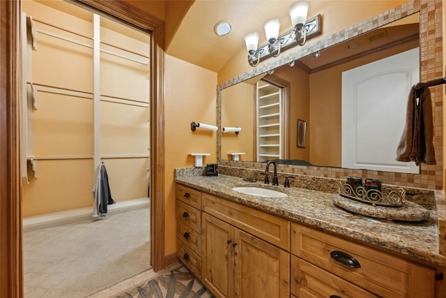 bathroom featuring a spacious closet, tasteful backsplash, and vanity