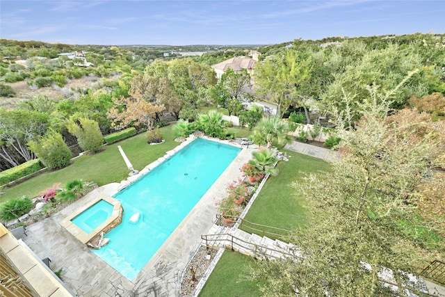 view of swimming pool featuring a lawn, fence, and a pool with connected hot tub