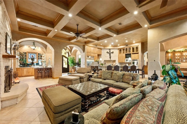 living area featuring arched walkways, crown molding, a fireplace, light tile patterned floors, and beamed ceiling