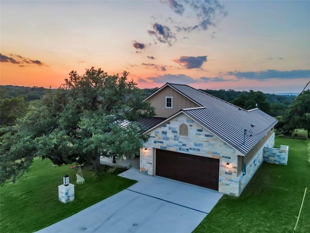 view of front of home with a standing seam roof, metal roof, a garage, stone siding, and driveway