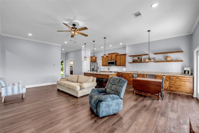 living area featuring baseboards, visible vents, dark wood finished floors, and ornamental molding