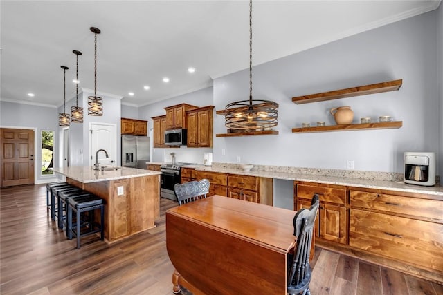 kitchen featuring decorative light fixtures, a kitchen island with sink, stainless steel appliances, a kitchen bar, and a sink