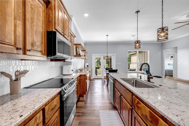 kitchen featuring brown cabinetry, light stone countertops, stainless steel appliances, pendant lighting, and a sink