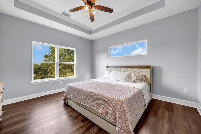 bedroom featuring dark wood-style floors, baseboards, visible vents, and a raised ceiling