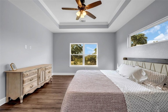 bedroom featuring dark wood-style floors, visible vents, multiple windows, and a tray ceiling