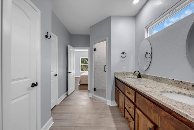 full bath featuring a sink, baseboards, a shower stall, double vanity, and ensuite bath