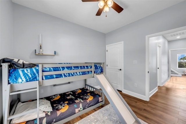 bedroom featuring a ceiling fan, baseboards, visible vents, and wood finished floors