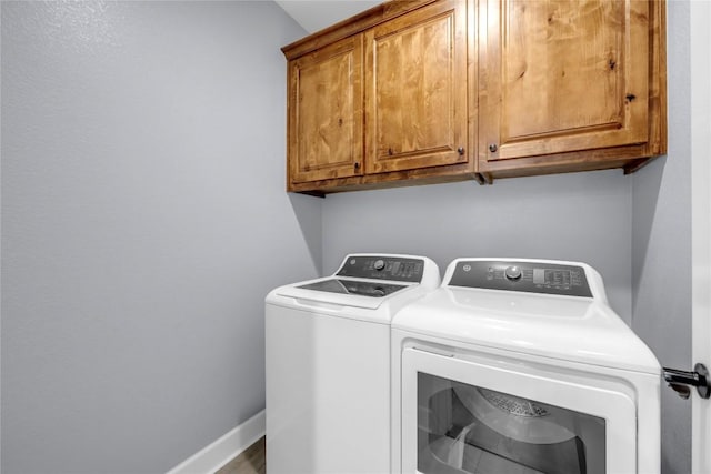 laundry room featuring cabinet space, baseboards, and separate washer and dryer