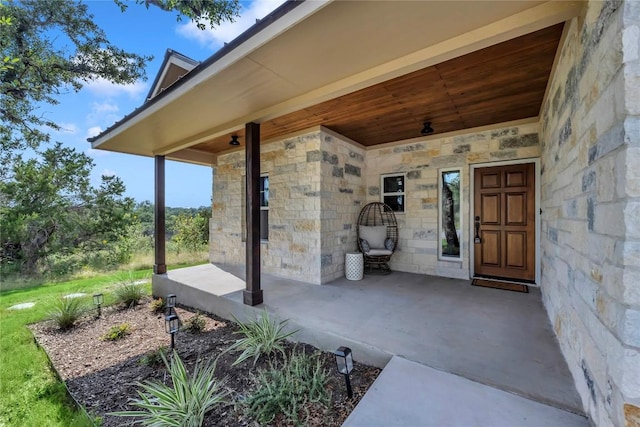 property entrance featuring stone siding and covered porch