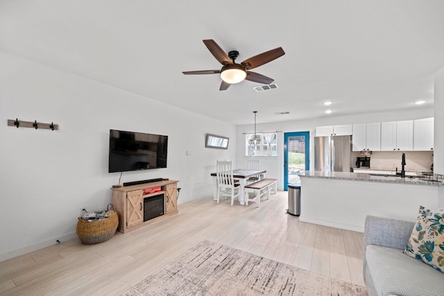 living room with light wood finished floors, visible vents, baseboards, ceiling fan, and recessed lighting