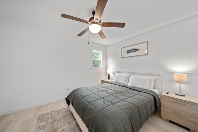 bedroom with ceiling fan, light wood-style flooring, and baseboards