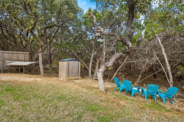 view of yard featuring a storage shed, fence, and an outdoor structure