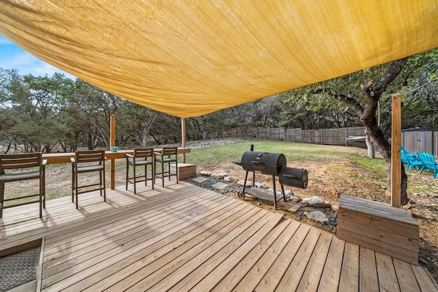 wooden deck featuring a yard, a fenced backyard, and a grill