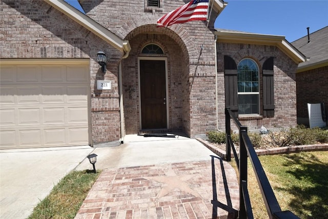 221 Joseph Dr, Buda, TX 78610 - property entrance with concrete driveway, brick siding, and a garage
