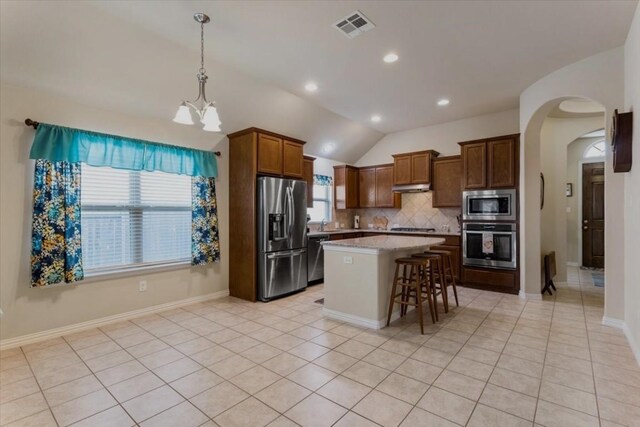 221 Joseph Dr, Buda, TX 78610 - kitchen with decorative backsplash, a kitchen bar, arched walkways, under cabinet range hood, and stainless steel appliances