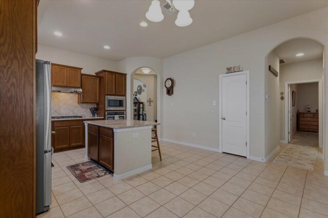 221 Joseph Dr, Buda, TX 78610 - kitchen featuring arched walkways, decorative backsplash, a center island, and appliances with stainless steel finishes