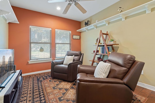 living area featuring baseboards, a ceiling fan, and wood finished floors