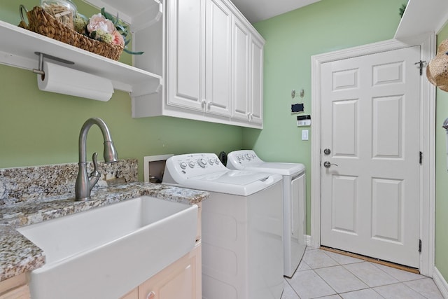 laundry room featuring washer and clothes dryer, light tile patterned floors, cabinet space, a sink, and baseboards