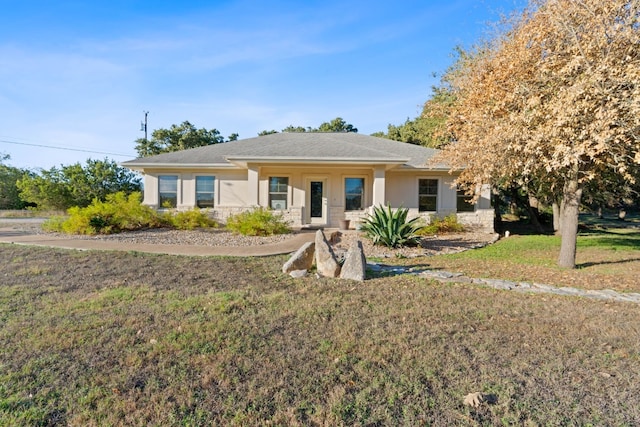 ranch-style home with stone siding, a front lawn, and stucco siding