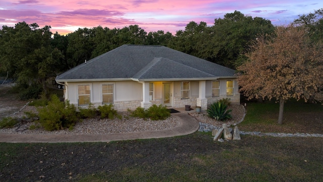 view of front of home featuring a shingled roof, stone siding, and stucco siding