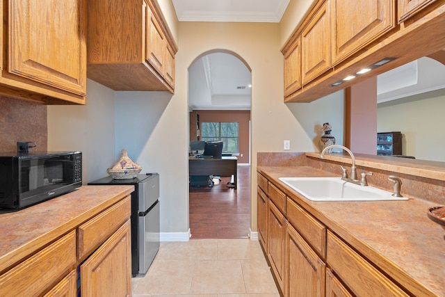 kitchen featuring light tile patterned floors, light countertops, crown molding, black microwave, and a sink