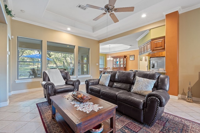 living area featuring a tray ceiling, crown molding, visible vents, light tile patterned flooring, and baseboards