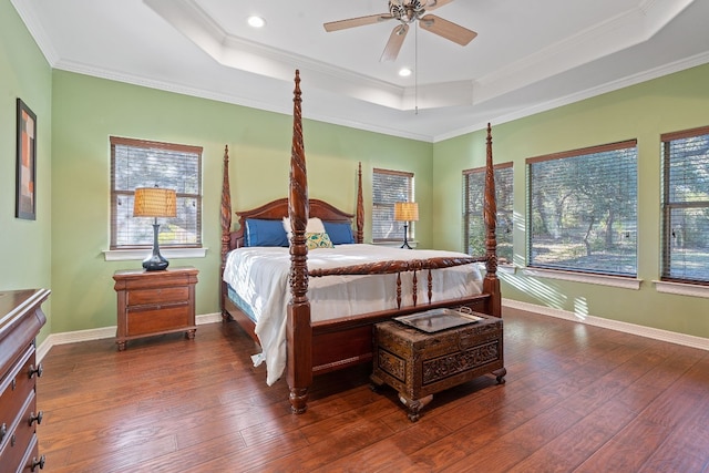 bedroom featuring baseboards, a raised ceiling, dark wood finished floors, and ornamental molding