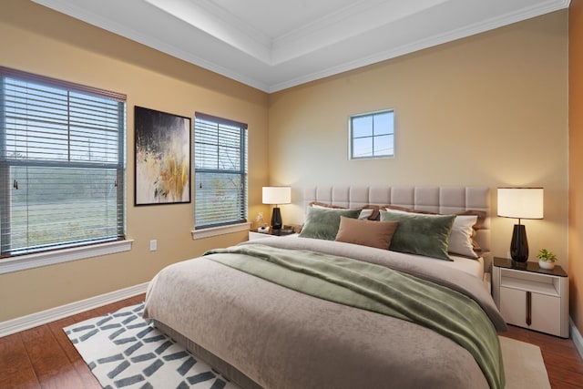 bedroom with baseboards, a tray ceiling, wood finished floors, and crown molding