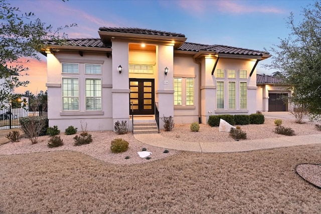 view of front of house featuring a tiled roof, french doors, an attached garage, and stucco siding