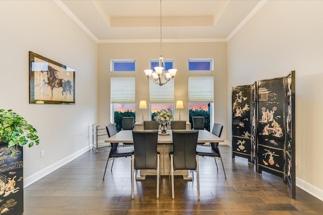 dining space with dark wood-type flooring, a raised ceiling, a notable chandelier, and baseboards