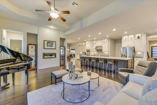 living area featuring a tile fireplace, recessed lighting, dark wood-type flooring, a ceiling fan, and visible vents