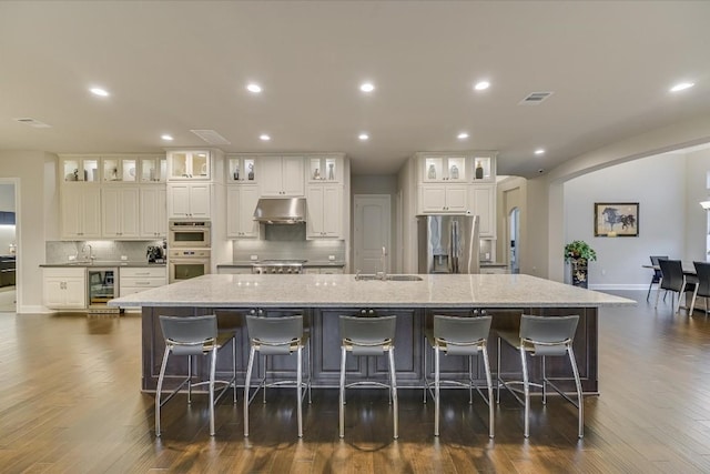 kitchen with stainless steel appliances, a breakfast bar, a spacious island, and glass insert cabinets