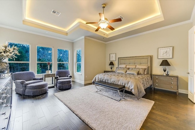 bedroom with ornamental molding, dark wood-style flooring, a raised ceiling, and visible vents