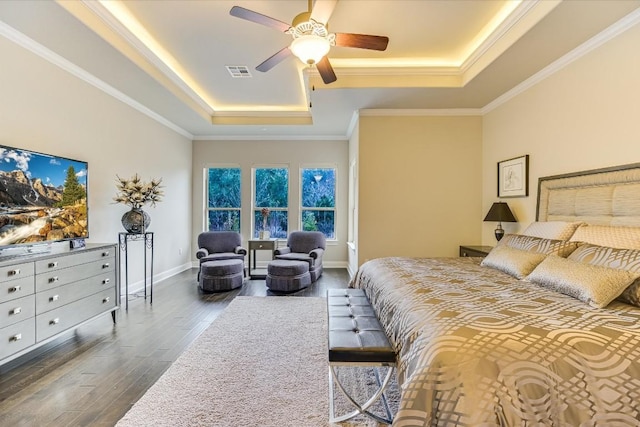 bedroom with dark wood-style flooring, crown molding, a raised ceiling, visible vents, and baseboards