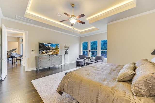 bedroom with a tray ceiling, dark wood-style flooring, and visible vents