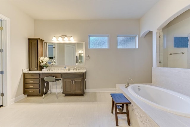 full bath with vanity, a bath, and baseboards