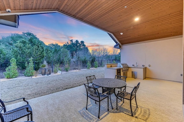 view of patio featuring outdoor dining area, area for grilling, a sink, fence, and exterior kitchen