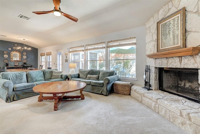 carpeted living room featuring a ceiling fan, visible vents, vaulted ceiling, and a stone fireplace