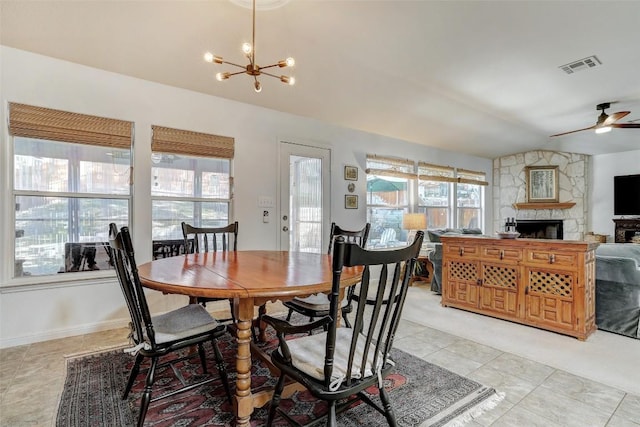 dining room featuring light tile patterned floors, visible vents, lofted ceiling, a fireplace, and ceiling fan with notable chandelier