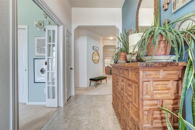 hallway featuring light tile patterned flooring and light colored carpet