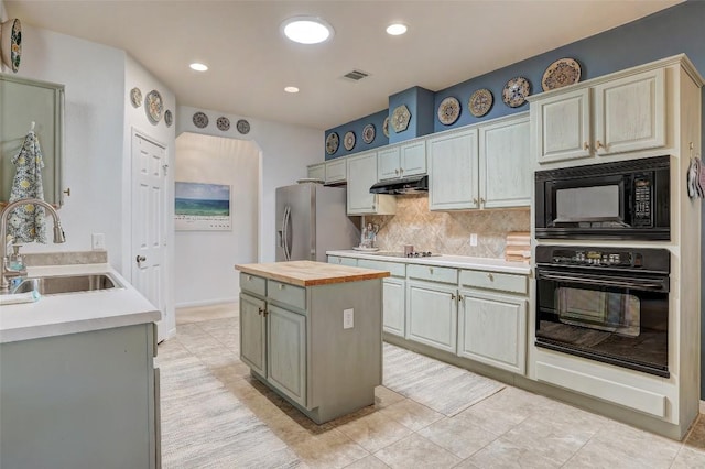 kitchen with a center island, under cabinet range hood, black appliances, wooden counters, and a sink