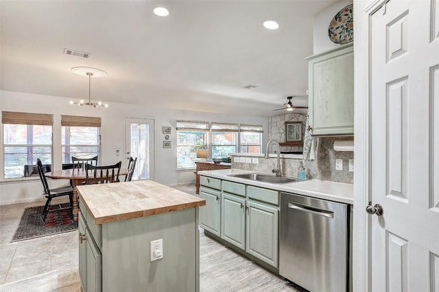 kitchen with visible vents, stainless steel dishwasher, a sink, a kitchen island, and butcher block countertops