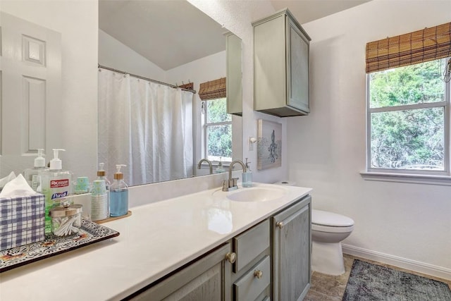 bathroom with lofted ceiling, baseboards, vanity, and toilet