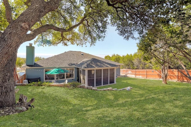 back of house with a yard, a chimney, a fenced backyard, and a sunroom